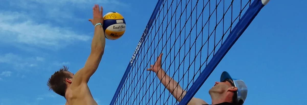 Angriff und Block am Netz, der Ball über der Netzkante, blauer Himmel